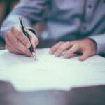 Image of hands signing papers that could be for wrongful death claim.