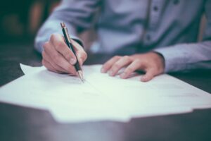 Image of hands signing papers that could be for wrongful death claim.