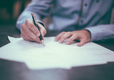 Image of hands signing papers that could be for wrongful death claim.