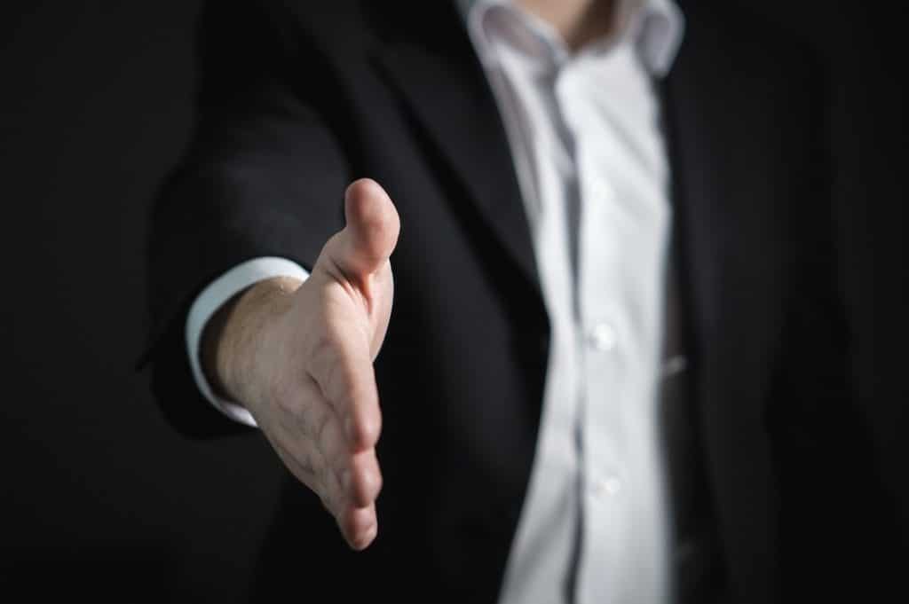 A man with his hand extended to shake someone else's hand. You can shake someones hand after hiring them for a job, but can you be held negligent?