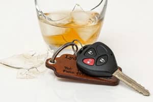 Los accidentes por conducir ebrio causan lesiones graves. Vidrio roto de alcohol fotografiado con un juego de llaves.