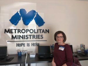 KFB Law Tampa Employee Helen poses in front of the Metropolitan Ministries logo
