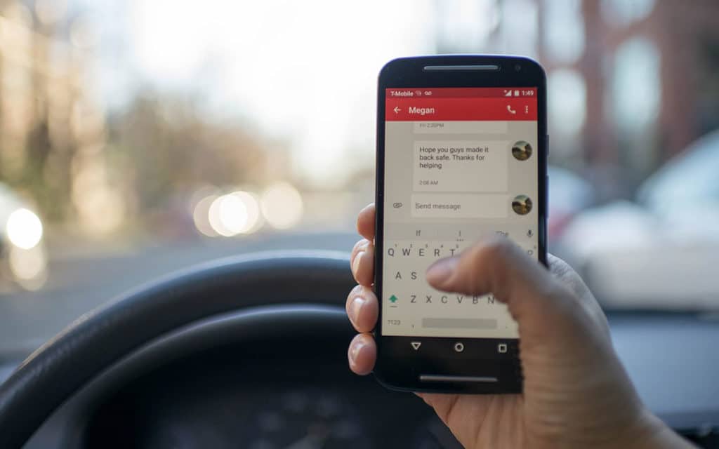 Imagen de persona enviando mensajes de texto mientras conduce un automóvil