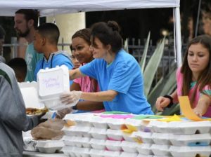 voluntarios proporcionando comidas a los invitados de 100 comidas