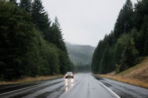 Car driving on an empty highway surrounded by trees