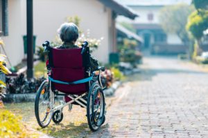 La anciana se sienta sola en una silla de ruedas al aire libre