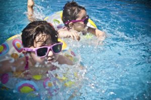 Niños nadando en la piscina con gafas de sol