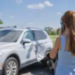 young woman on cell phone after minor car accident wondering do you have to call police after an accident
