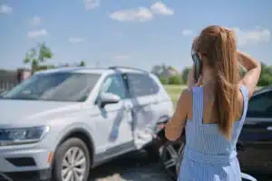 young woman on cell phone after minor car accident wondering do you have to call police after an accident